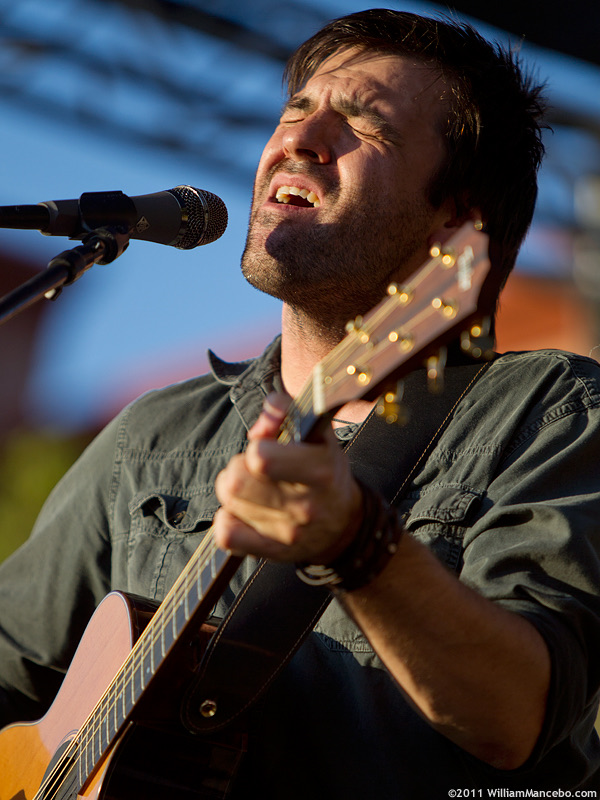 Nathan Dale singing and playing acoustic guitar during a solo performance in 2011