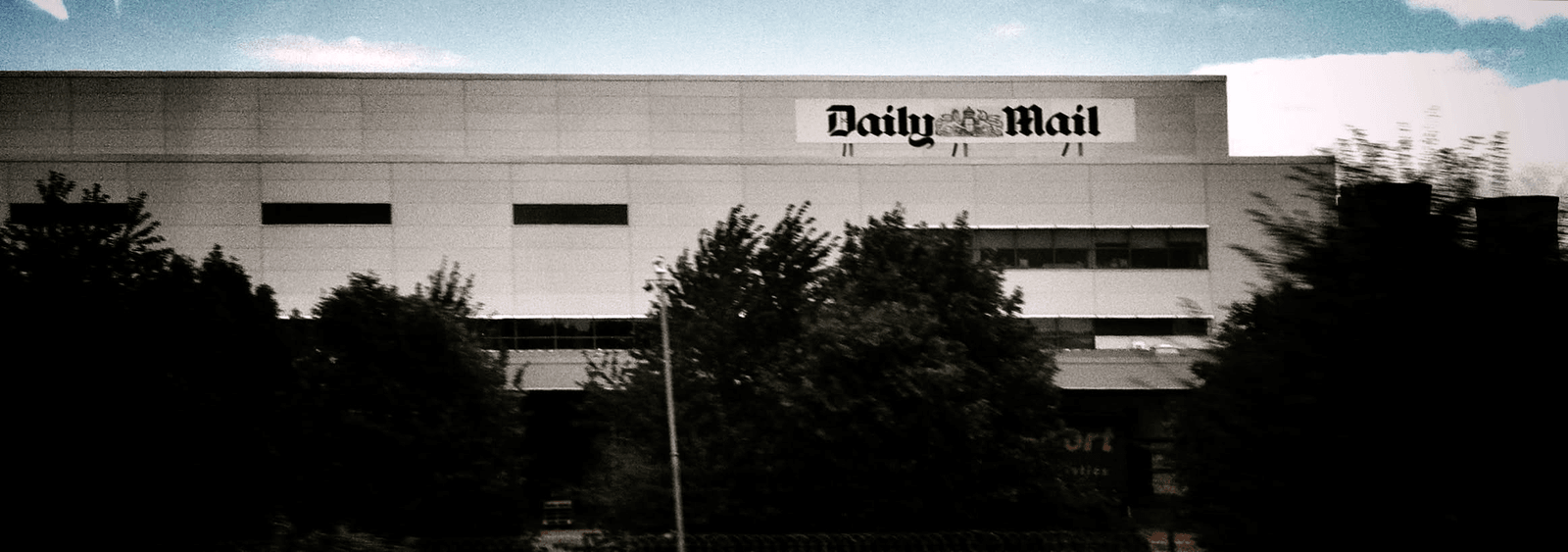 The Daily Mail building seen past trees from a moving vehicle