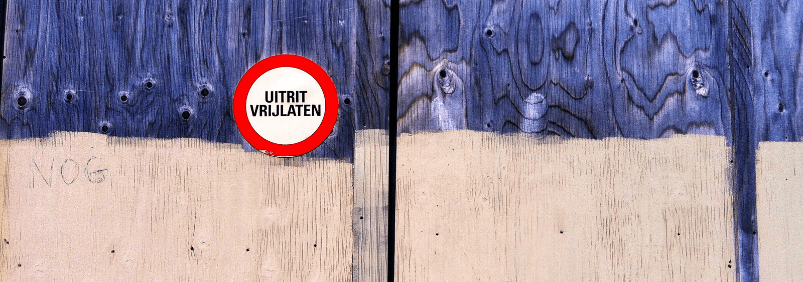 An exit sign mounted on weathered blue boards